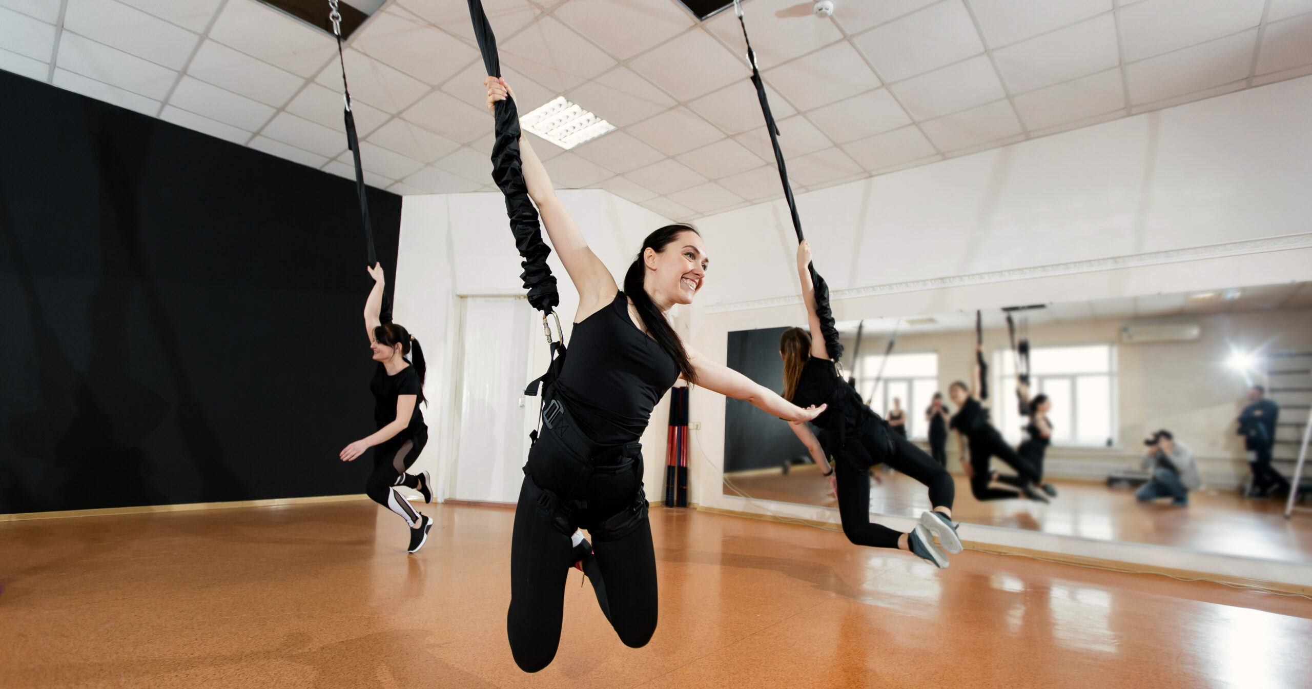 Group of active sports girls in black sportswear are engaged in budgie fitness in the gym. Bungee jumping in the gym